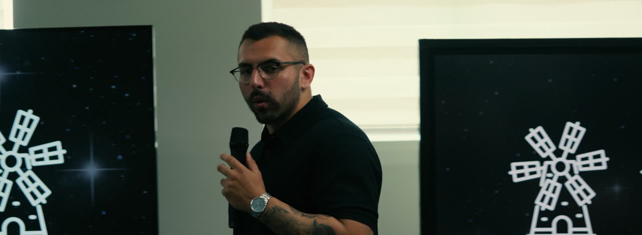 O professor de tráfego falando entre duas telas com o moinho de marketing, na sala