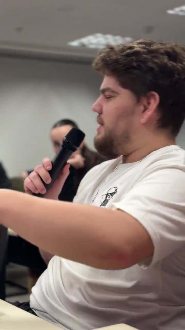 Um dentista falando ao microfone na roda de abertura, sentado na sala